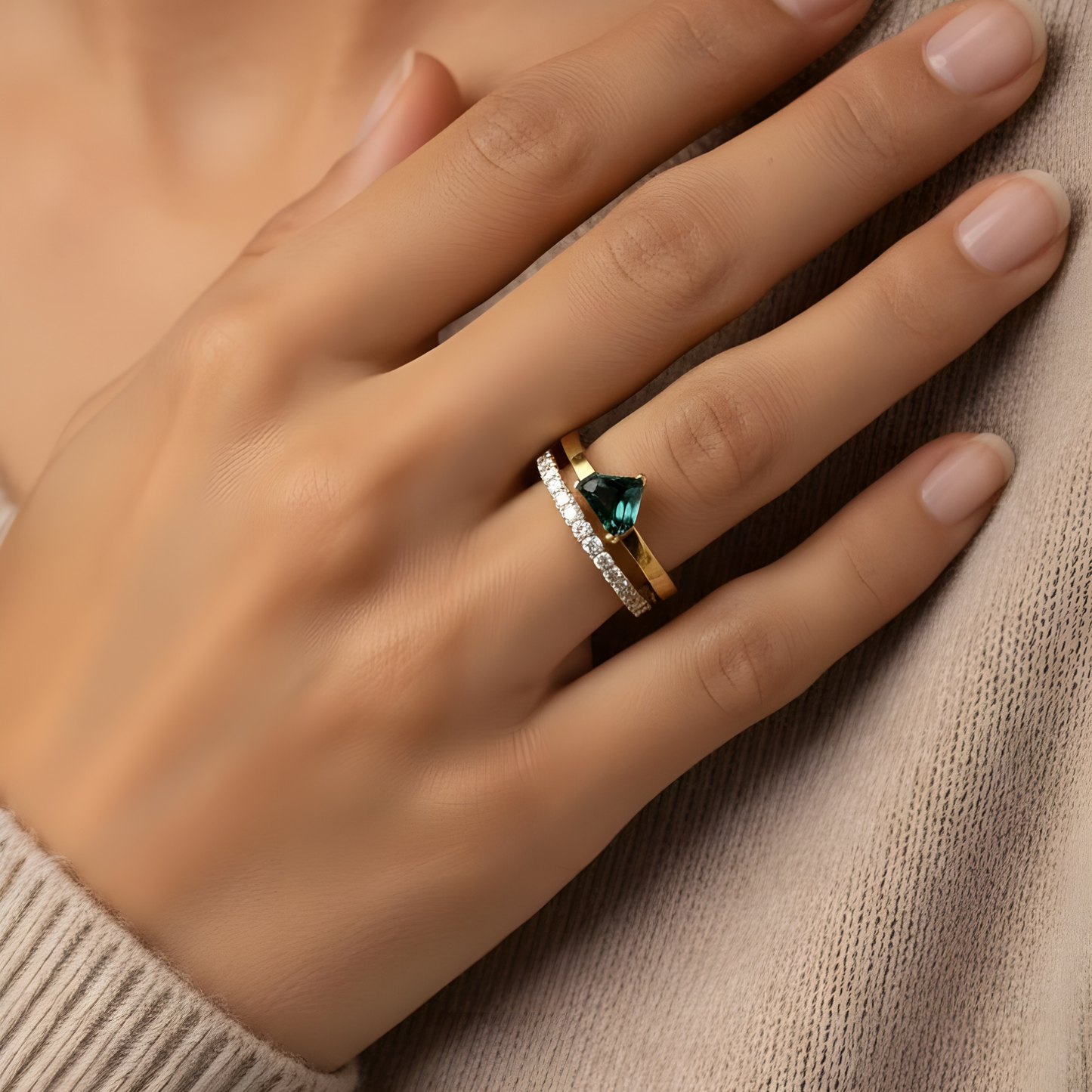 Hand wearing a gold ring with a blue green parti sapphire double gold band set with a pave of diamonds